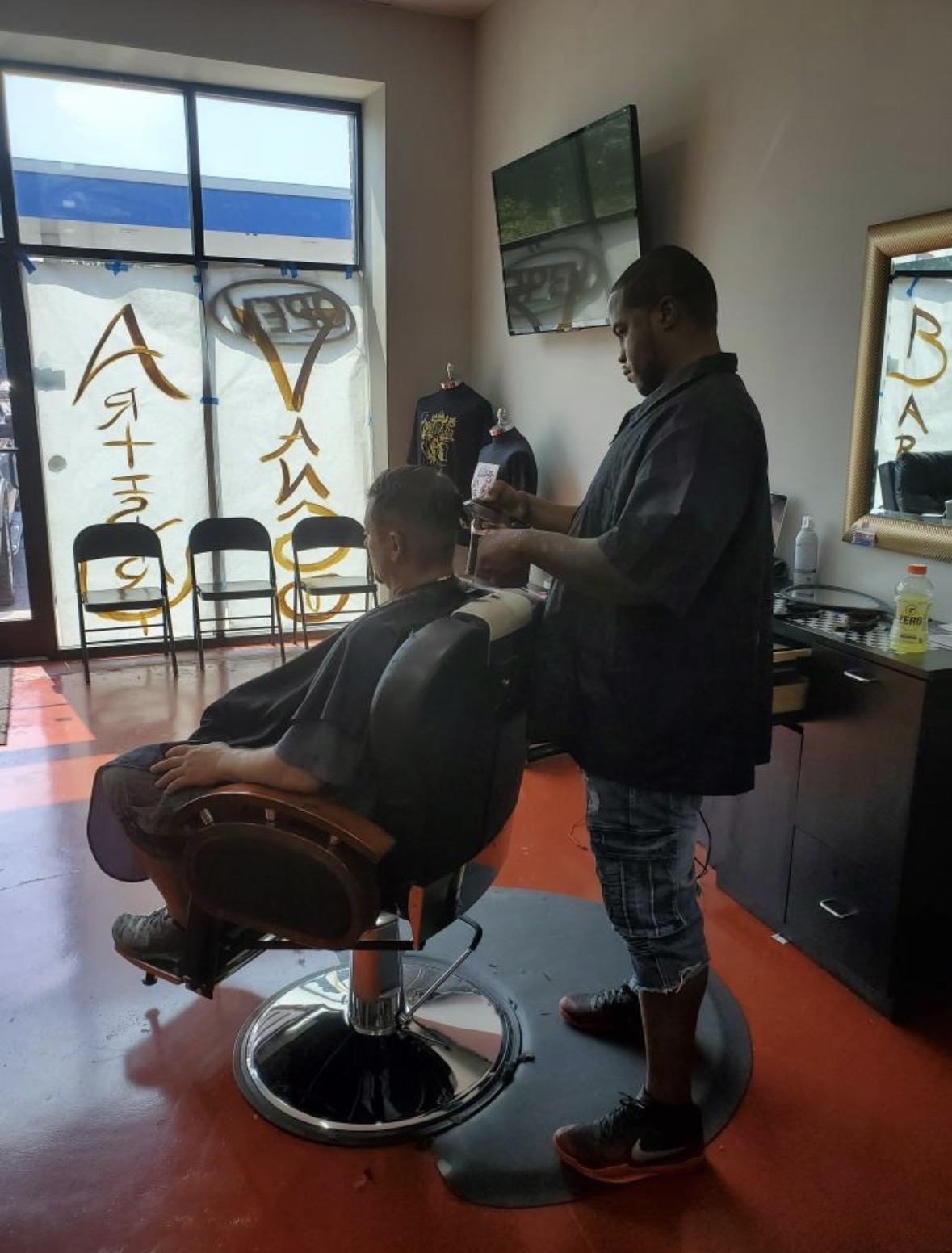 Mr. P cutting a client's hair in his barber chair at the shop